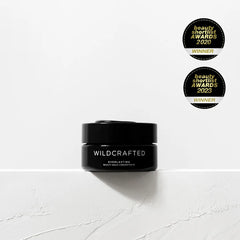 Black jar labeled 'Wildcrafted' on a white background with two awards above it.